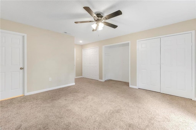 unfurnished bedroom featuring carpet floors, baseboards, ceiling fan, and two closets