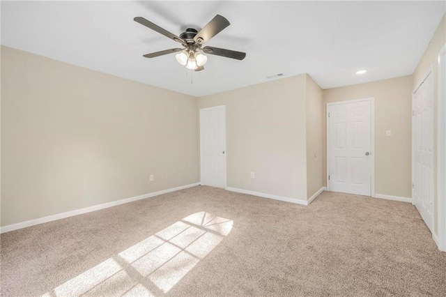 unfurnished bedroom featuring visible vents, baseboards, ceiling fan, and light carpet