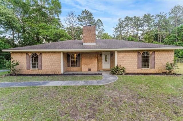 ranch-style home featuring brick siding, a chimney, and a front lawn