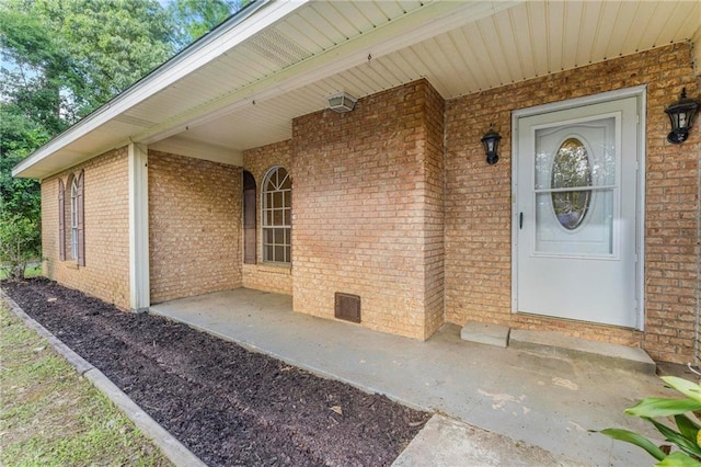doorway to property with covered porch and brick siding