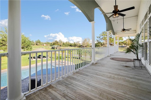 wooden terrace featuring ceiling fan and a fenced in pool