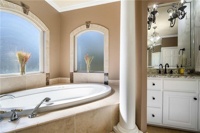 bathroom featuring tiled tub, crown molding, vanity, and ornate columns