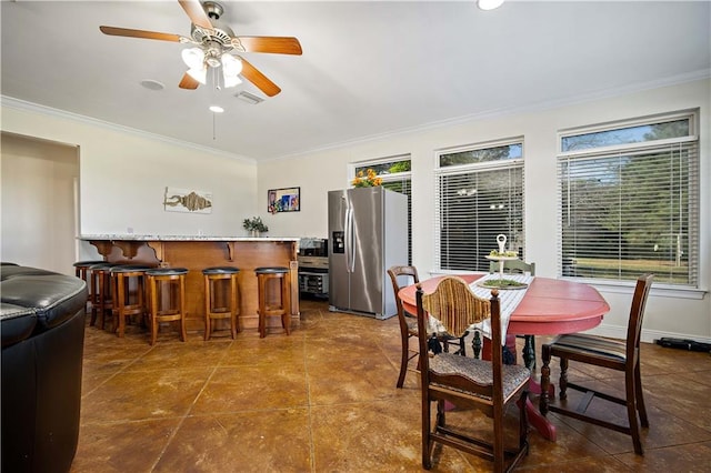 tiled dining room featuring ceiling fan, ornamental molding, and bar area