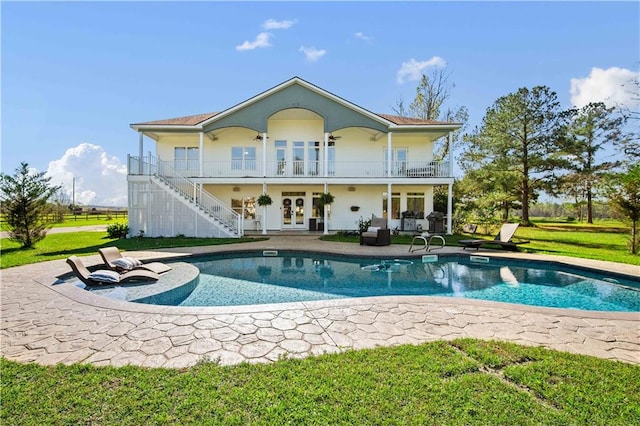 rear view of property with french doors, a balcony, a patio area, and a lawn