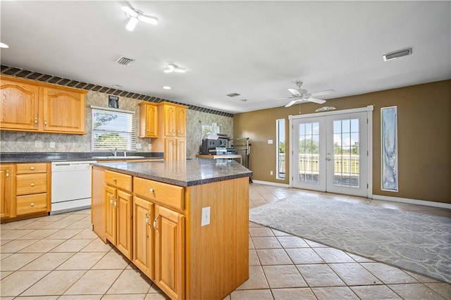 kitchen featuring dishwasher, a center island, french doors, ceiling fan, and tasteful backsplash