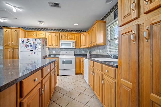 kitchen with sink, tasteful backsplash, dark stone countertops, white appliances, and light tile patterned flooring