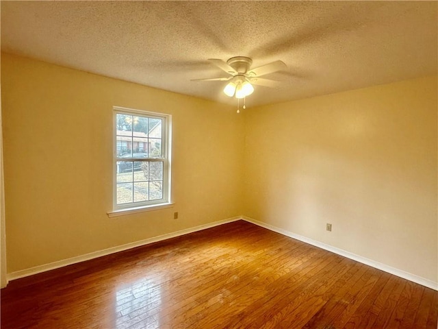 empty room featuring dark wood-type flooring, ceiling fan, and a textured ceiling