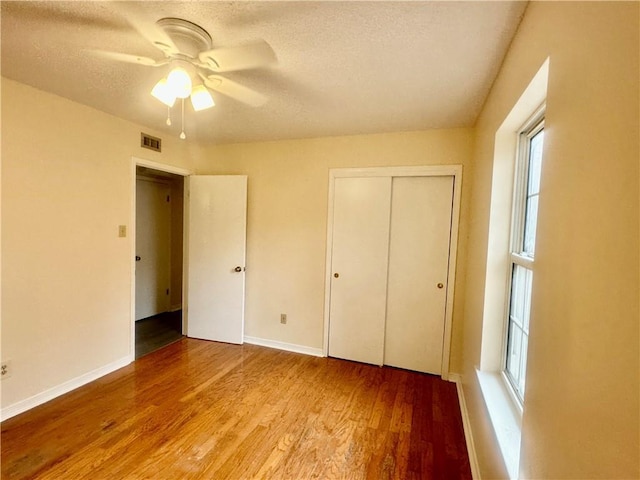 unfurnished bedroom with ceiling fan, a closet, a textured ceiling, and light wood-type flooring