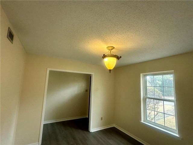 unfurnished room with a textured ceiling and dark hardwood / wood-style flooring