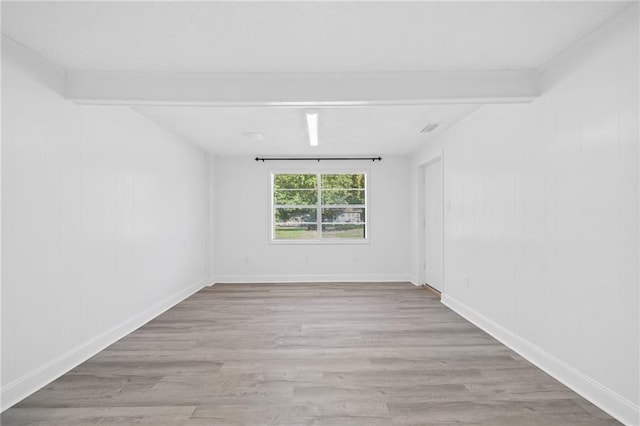 spare room with beam ceiling and light wood-type flooring