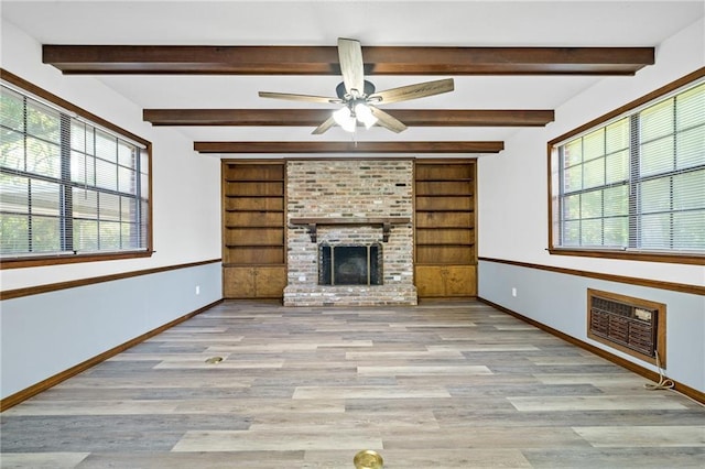 unfurnished living room featuring a brick fireplace, built in features, and a wealth of natural light