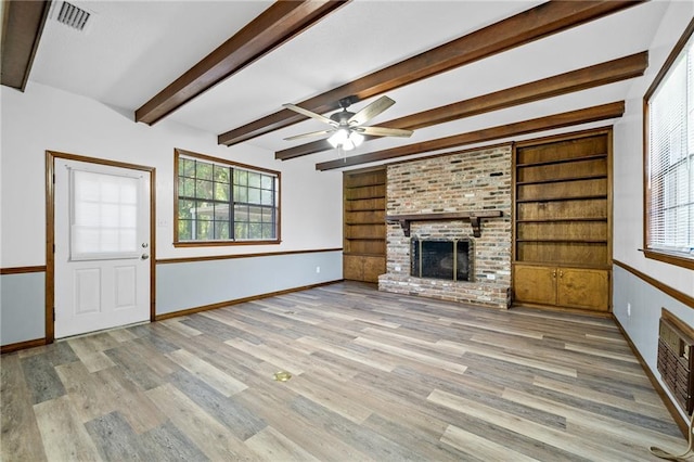 unfurnished living room featuring ceiling fan, built in features, light hardwood / wood-style flooring, and a brick fireplace