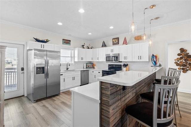 kitchen featuring a peninsula, a sink, light wood-style floors, and appliances with stainless steel finishes