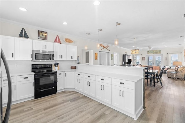 kitchen featuring light countertops, stainless steel microwave, a peninsula, black range with electric cooktop, and open floor plan