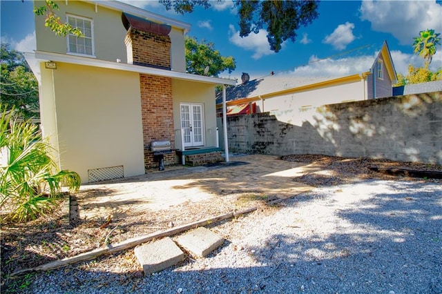 211 Cedar St, Mobile, AL 36602 - back of property featuring french doors, a patio area, brick siding, and stucco siding