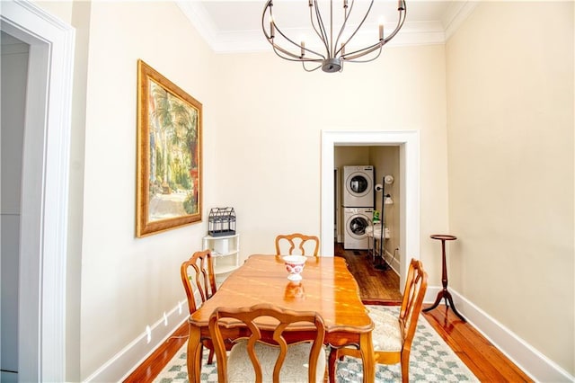 211 Cedar St, Mobile, AL 36602 - dining area with stacked washer and clothes dryer, ornamental molding, a chandelier, and wood finished floors