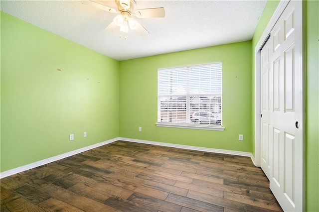 unfurnished bedroom with a textured ceiling, dark hardwood / wood-style flooring, a closet, and ceiling fan