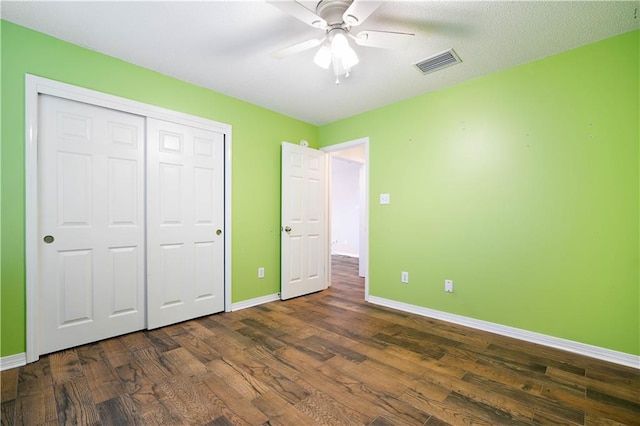 unfurnished bedroom featuring ceiling fan, dark hardwood / wood-style floors, a textured ceiling, and a closet