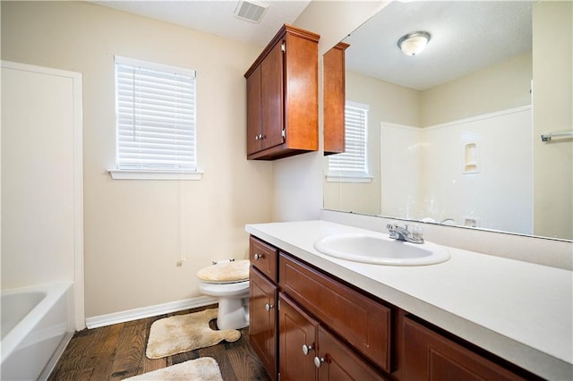 full bathroom featuring plenty of natural light, vanity, wood-type flooring, and toilet