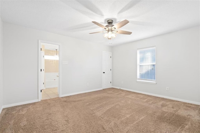 unfurnished room featuring baseboards, ceiling fan, a textured ceiling, and carpet