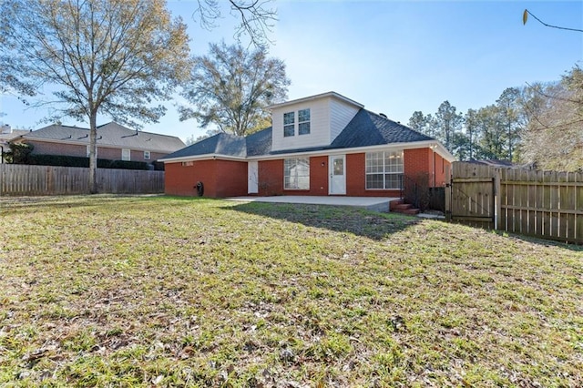 back of property with a patio area, a fenced backyard, brick siding, and a yard