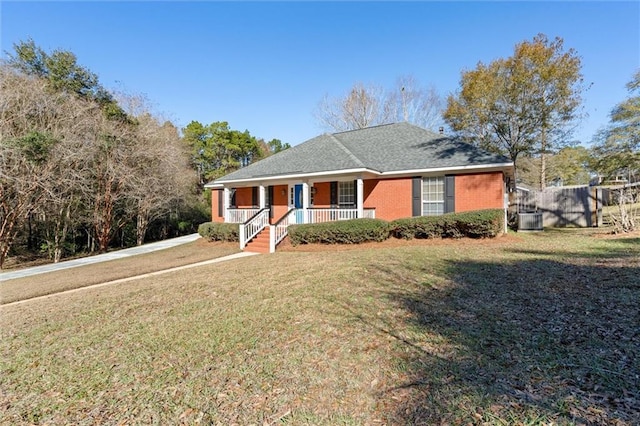 view of front of house with central AC, fence, covered porch, a front yard, and brick siding