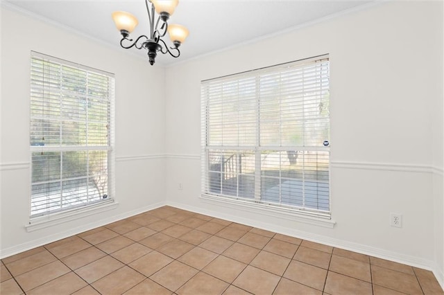 spare room featuring baseboards, a chandelier, and crown molding