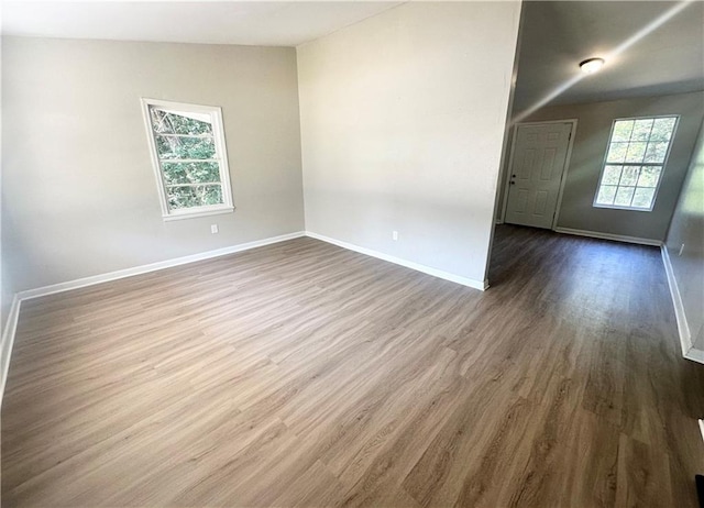 spare room featuring hardwood / wood-style floors and vaulted ceiling