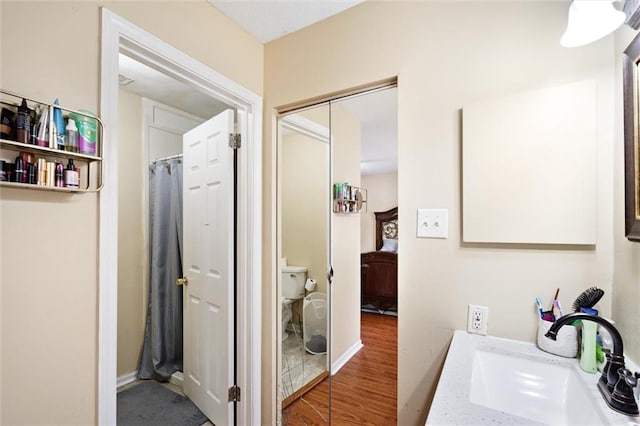 bathroom featuring toilet, wood-type flooring, and sink