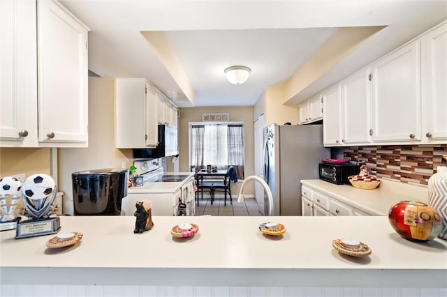 kitchen featuring light tile flooring, backsplash, white cabinets, and white appliances