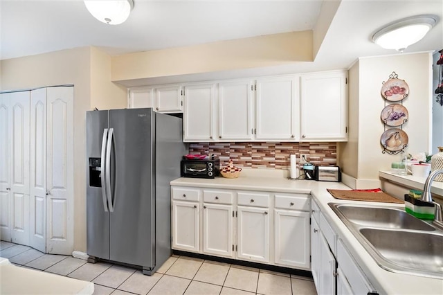 kitchen with light tile flooring, backsplash, white cabinetry, and stainless steel fridge