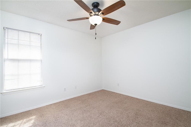 carpeted spare room with baseboards, ceiling fan, and a healthy amount of sunlight