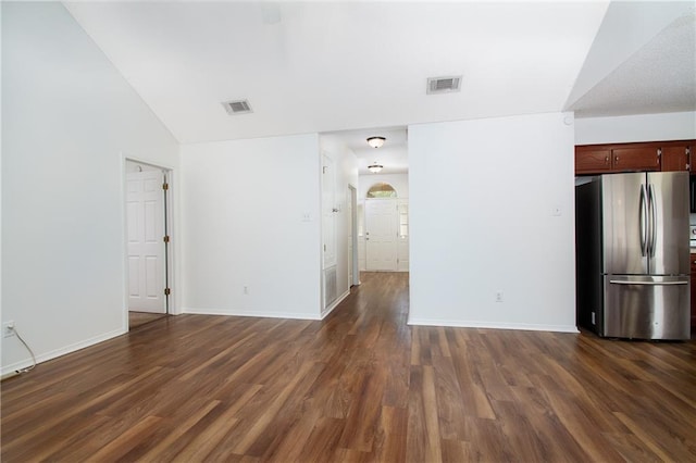 interior space featuring baseboards, lofted ceiling, dark wood-style floors, and visible vents