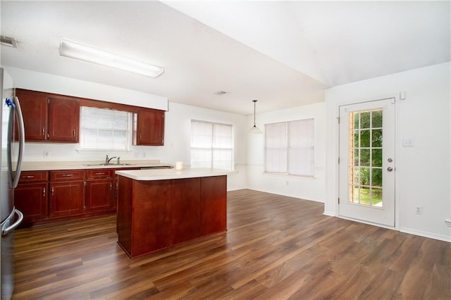 kitchen with light countertops, dark brown cabinets, dark wood finished floors, and a sink