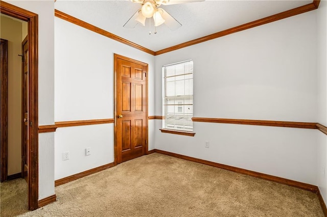 unfurnished room featuring a ceiling fan, baseboards, ornamental molding, and carpet flooring