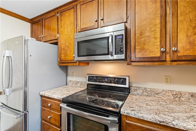 kitchen featuring appliances with stainless steel finishes, brown cabinets, and crown molding