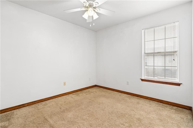 empty room featuring light carpet, a ceiling fan, and baseboards