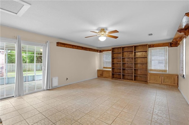 empty room with baseboards, a ceiling fan, and visible vents