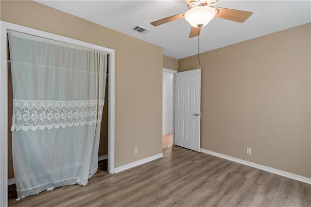 unfurnished bedroom featuring wood finished floors, baseboards, a ceiling fan, and visible vents