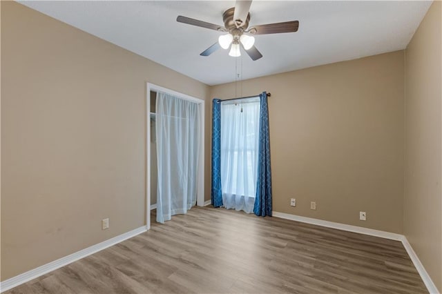 unfurnished room featuring ceiling fan, wood finished floors, and baseboards
