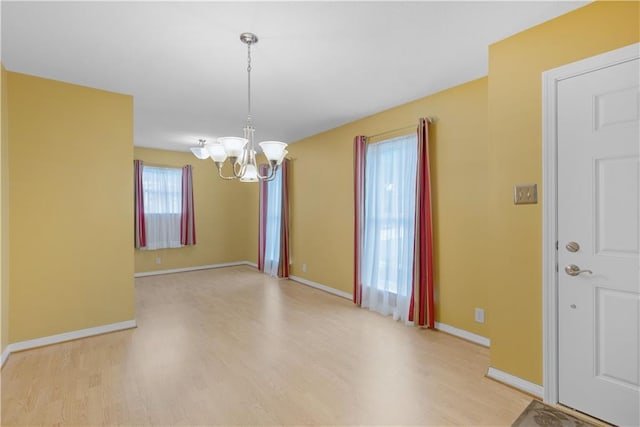 interior space featuring baseboards, light wood finished floors, and a chandelier