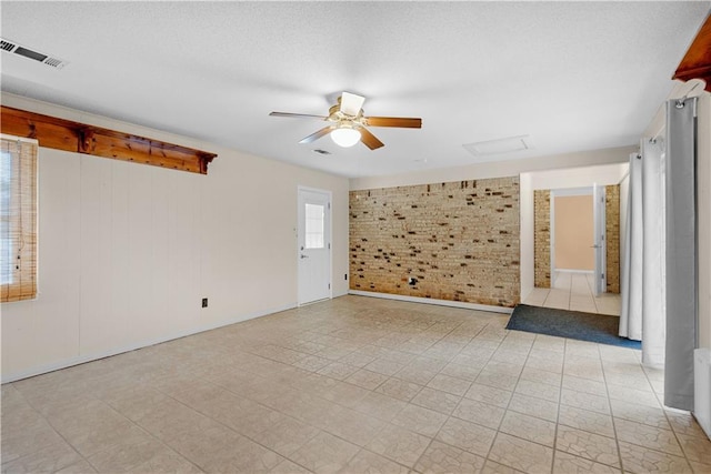 empty room featuring brick wall, visible vents, a textured ceiling, and ceiling fan