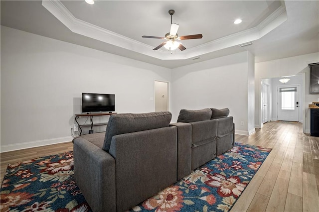 living area featuring crown molding, wood finished floors, and a raised ceiling