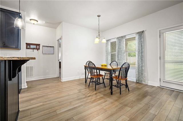 dining area featuring baseboards, visible vents, an inviting chandelier, and light wood finished floors