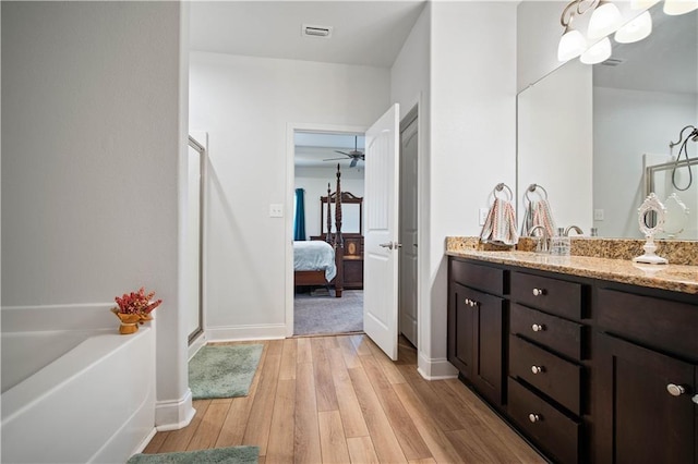 ensuite bathroom featuring vanity, connected bathroom, a stall shower, visible vents, and wood finished floors