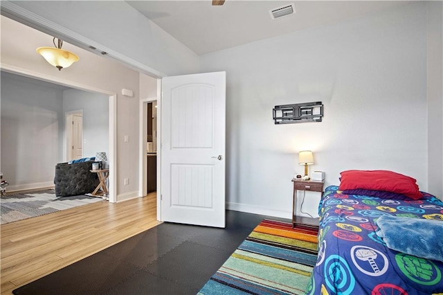 bedroom featuring baseboards, visible vents, and wood finished floors