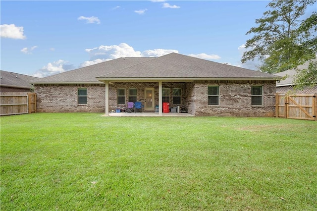 back of house with a fenced backyard, brick siding, a lawn, and a patio area