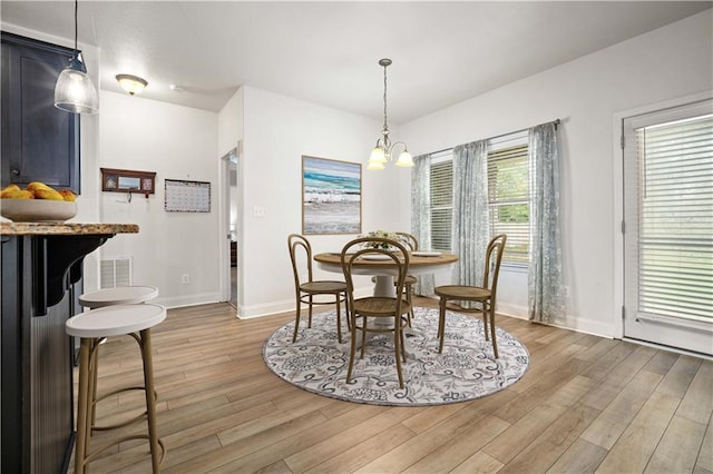 dining space featuring baseboards, light wood-style floors, and a notable chandelier