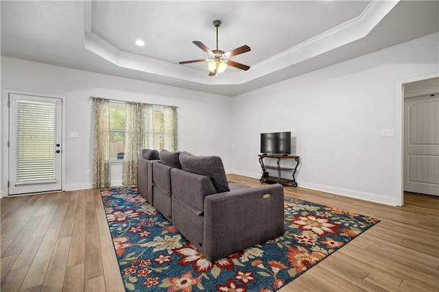 living area with wood finished floors, a tray ceiling, ceiling fan, and crown molding