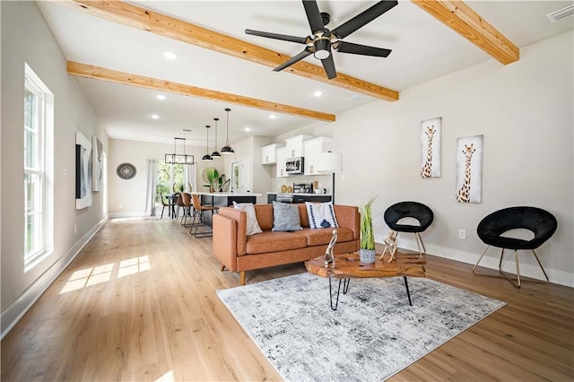 living room with beam ceiling, ceiling fan, and light hardwood / wood-style flooring